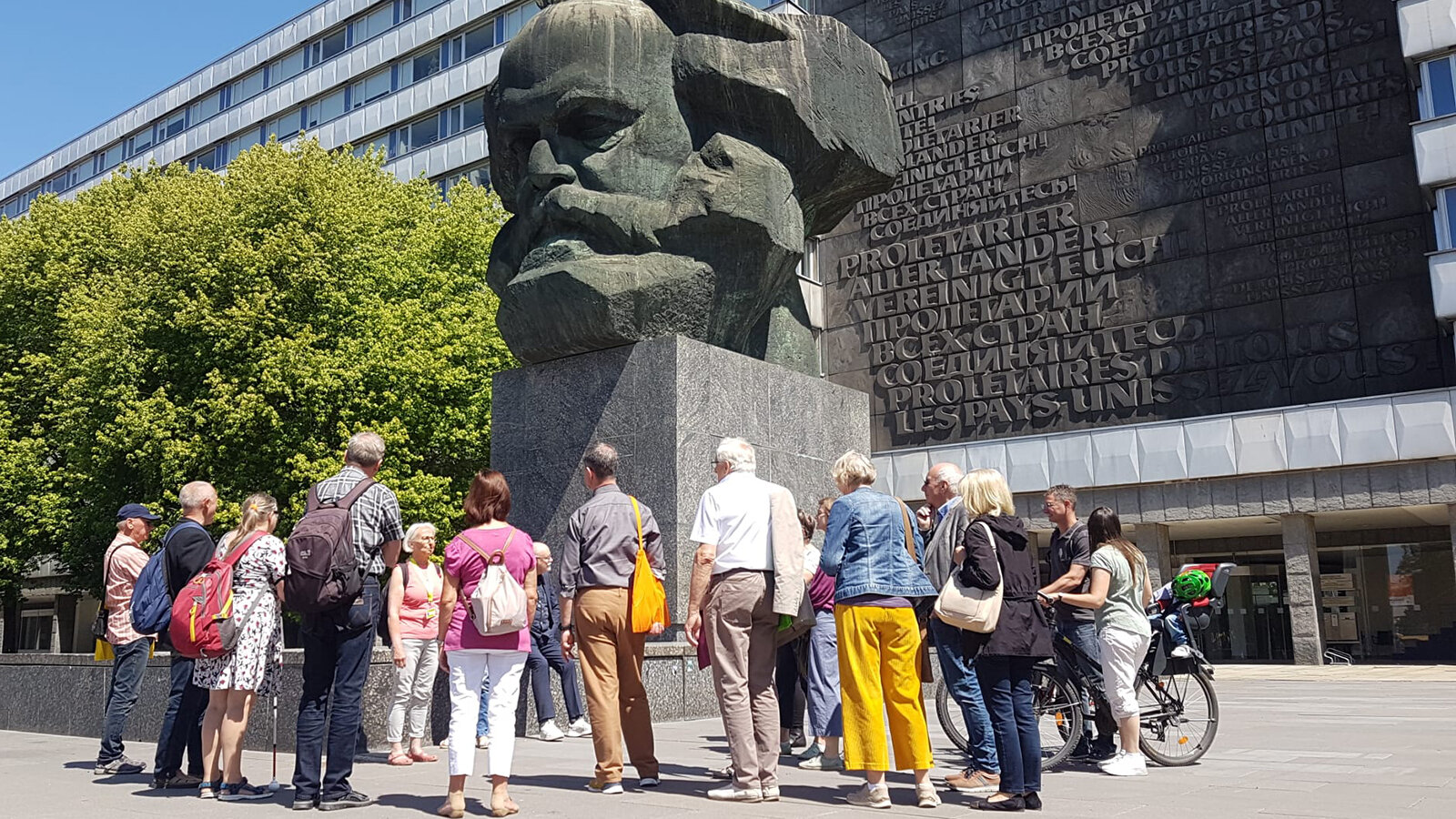 Mehrere Personen stehen vor einer großen Büste von Karl Marx im Stadtzentrum von Chemnitz. 