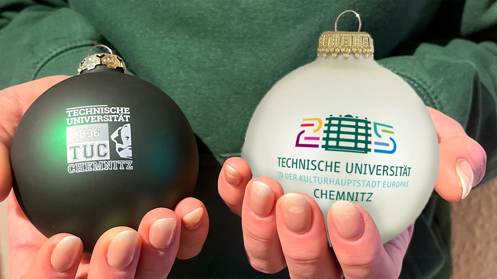 Two hands holding Christmas baubles.