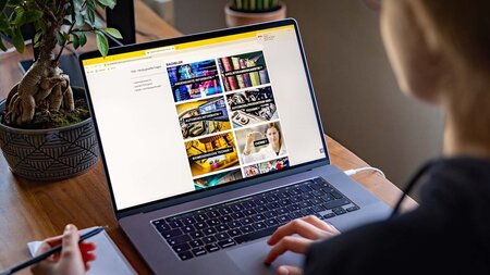 Ein Frau sitzt vor einem Laptop.