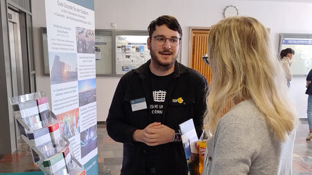 Ein Mann spricht an einem Messestand mit einer Frau.