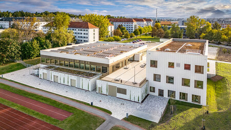 Blick auf zwei Gebäude neben einem Sportplatz.