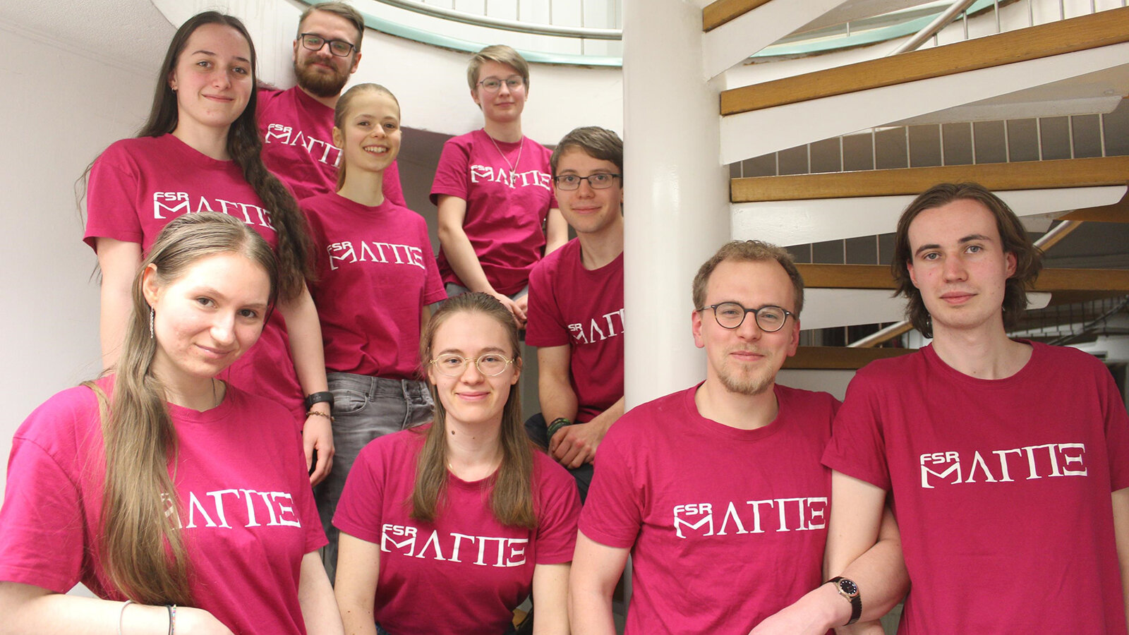 Mehrere Personen stehen auf einer Wendeltreppe.