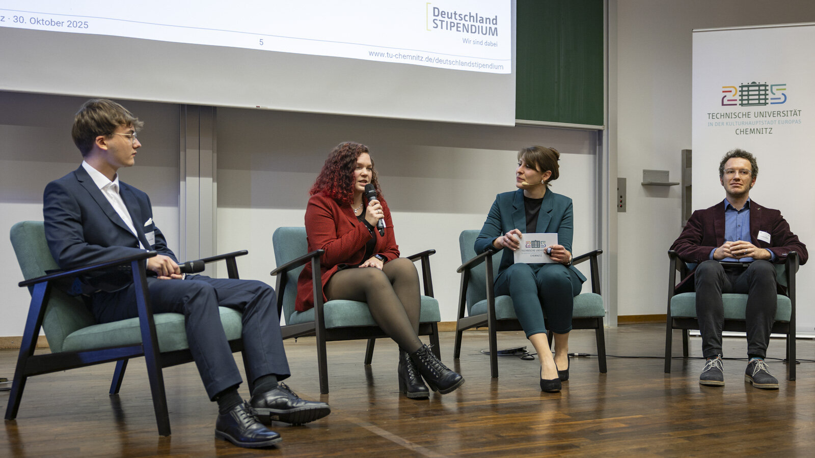 Zwei Frauen und zwei Männer sitzen nebeneinander auf Sesseln.