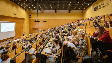 Mehrere Personen sitzen in einem Hörsaal.
