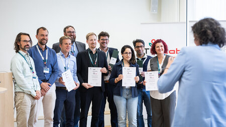 Mehrere Personen stehen nebeneinander und halten Blumen und Urkunden in den Händen.