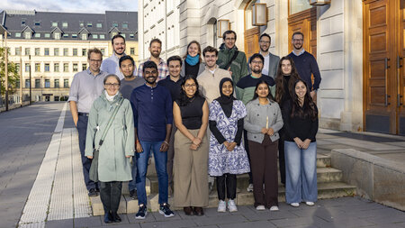 Mehrere Personen stehen auf einer Treppe vor einem Gebäude.