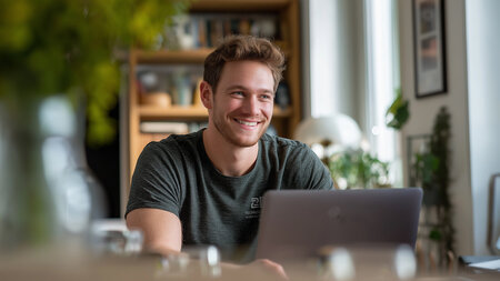 Ein junger Mann sitzt am Laptop.