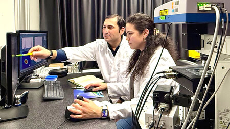 A man and a woman are working on a computer.