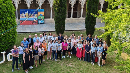 Mehrere Personen stehen auf einem Rasen vor einem Gebäude.