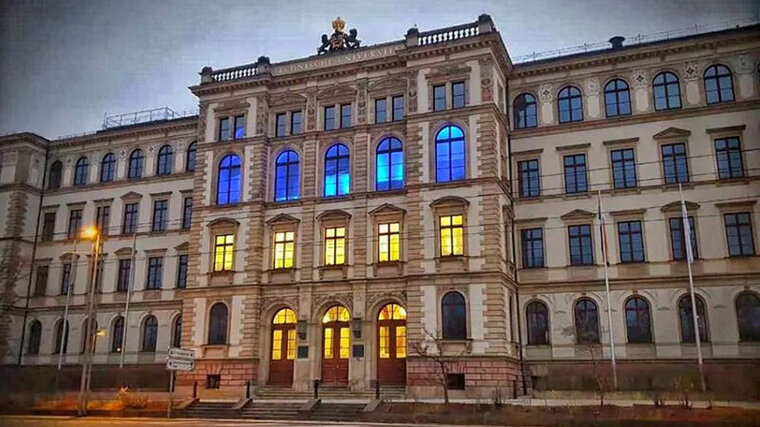 Gelb und blau angeleuchtete Fenster eines historischen Gebäudes.