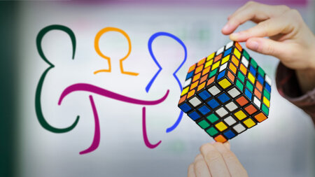 Zwei Hände halten einen Zauberwürfel, daneben ist ein bintes Logo zu sehen.