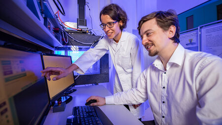 Eine Frau und ein Mann arbeiten im Labor an einem Computer.