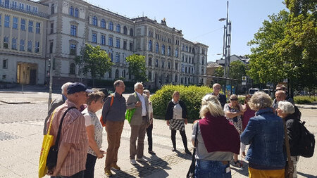 Mehrere Personen stehen an einer Stra�enkreuzung vor einem Geb�ude.