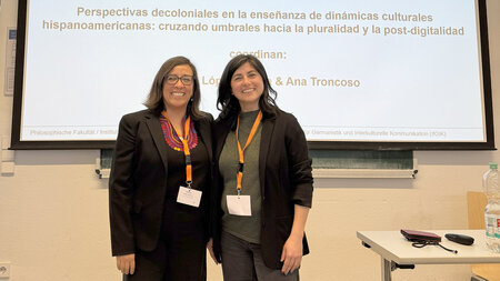 Zwei Frauen stehen nebeneinander vor einem Bildschirm.