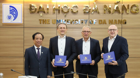 Vier M�nner in Anz�gen stehen vor einer Pr�sentationswand, drei der M�nner halten eine Schatulle in den H�nden.