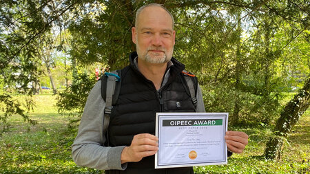 Ein Mann hält eine Urkunde in den Händen.