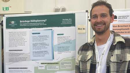 Ein junger Mann steht neben einem großen Poster.