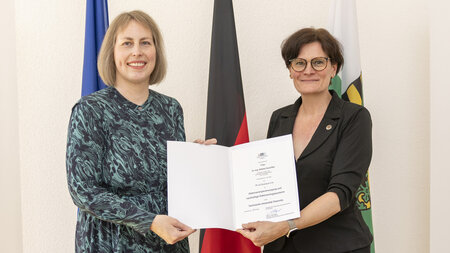 Zwei Frauen halten eine Urkunde in den Händen.