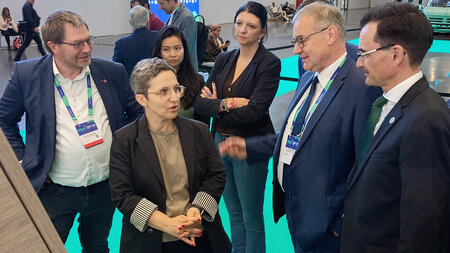 Mehrere Personen sprechen an einem Messestand miteinander.