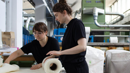 Zwei Frauen arbeiten mit Textilabfällen.
