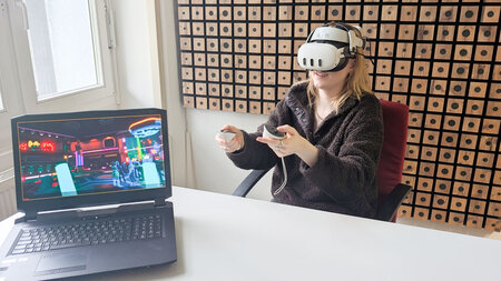Frau hat eine VR-Brille auf und zwei Controller in der Hand