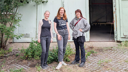 Drei Frauen stehen vor dem Eingang einer Halle