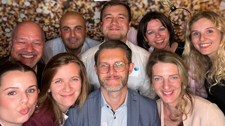 9 Menschen schauen in die Kamera