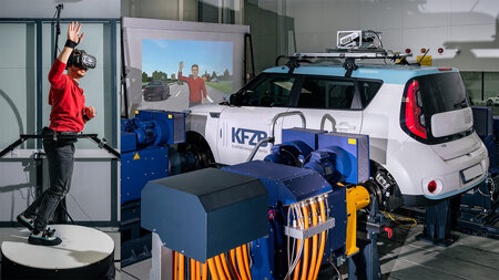 A woman wearing VR goggles is standing next to a car in a laboratory.