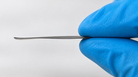 Fingerspitzen halten ein schwarzes Material