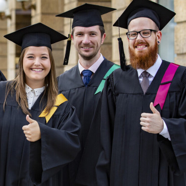 Alumni in hats and gowns happy about their graduation.