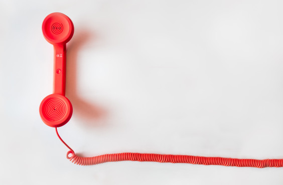 A red corded telephone on white ground.