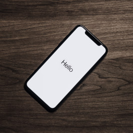 A Smartphone with the word Hello on its display is lying on a table.