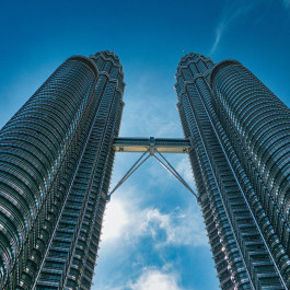 Bild zeigt zwei Hochhäuser, die Petronas Towers in Kuala Lumpur, vor blauem Himmel
