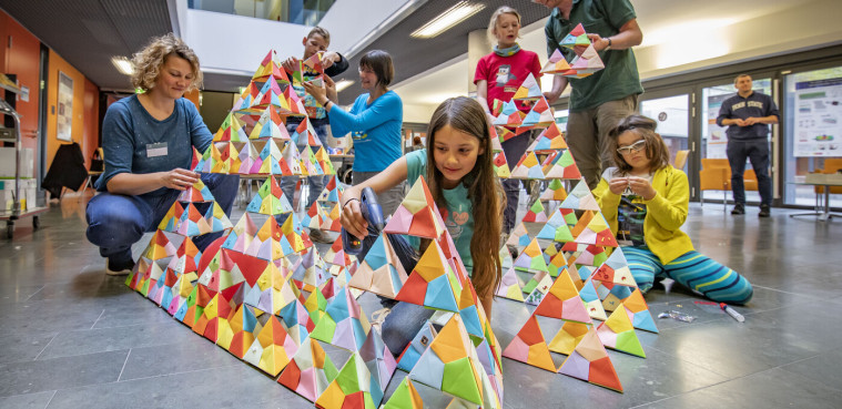 Children build a fractal out of paper triangles