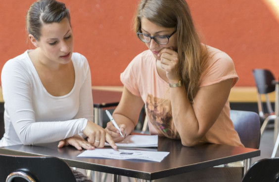 Zwei Studentinnen sitzen zusammen an einem Tisch