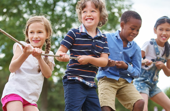 Vier Kinder ziehen gemeinsam an einem Seil.