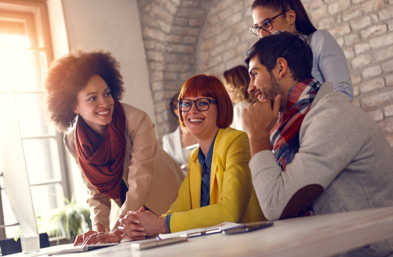 Eine Gruppe Menschen arbeitet gemeinsam an einem Computer.