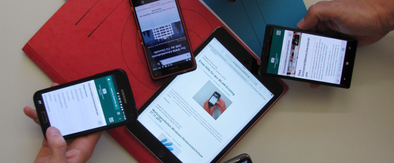 mehrere Hände halten verschiedene Mobilgeräte