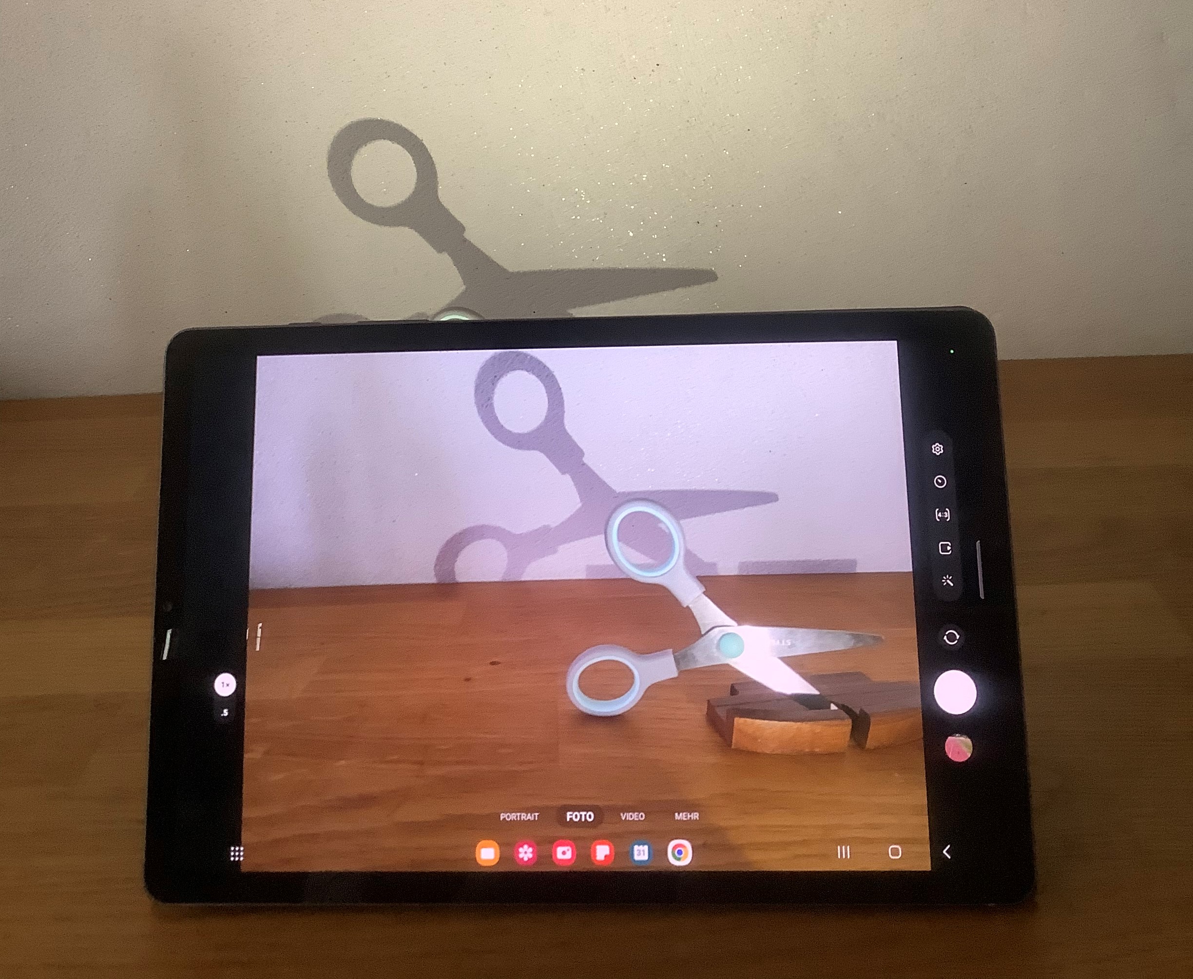 Das Foto zeigt ein Tablet, welches gerade mit der Kamerafunktion eine Schere und dessen Schatten aufnimmt.